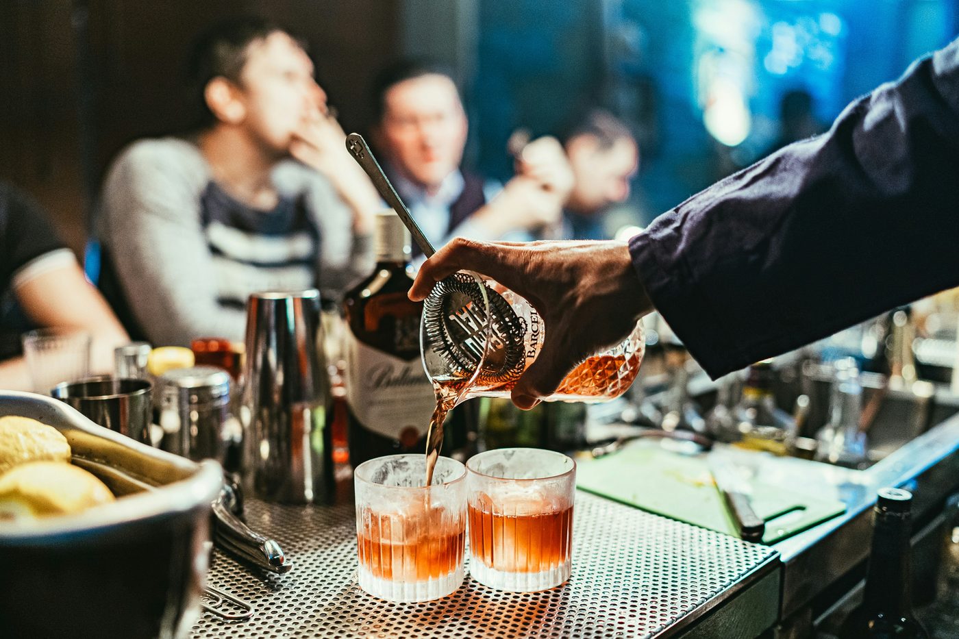 A bartender pouring a drink behind the counter at Noir House