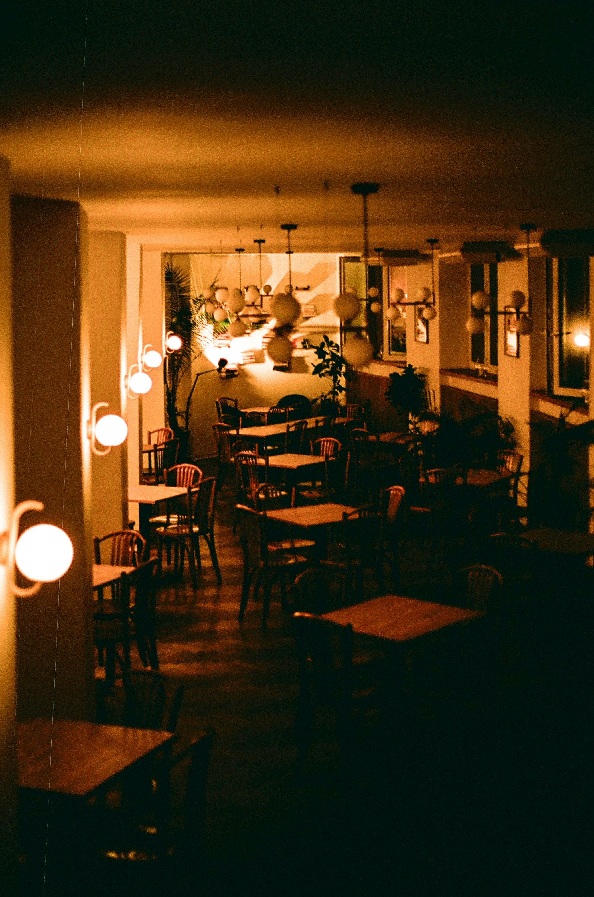 Dimly lit dining room at Noir House, tables set under warm low light